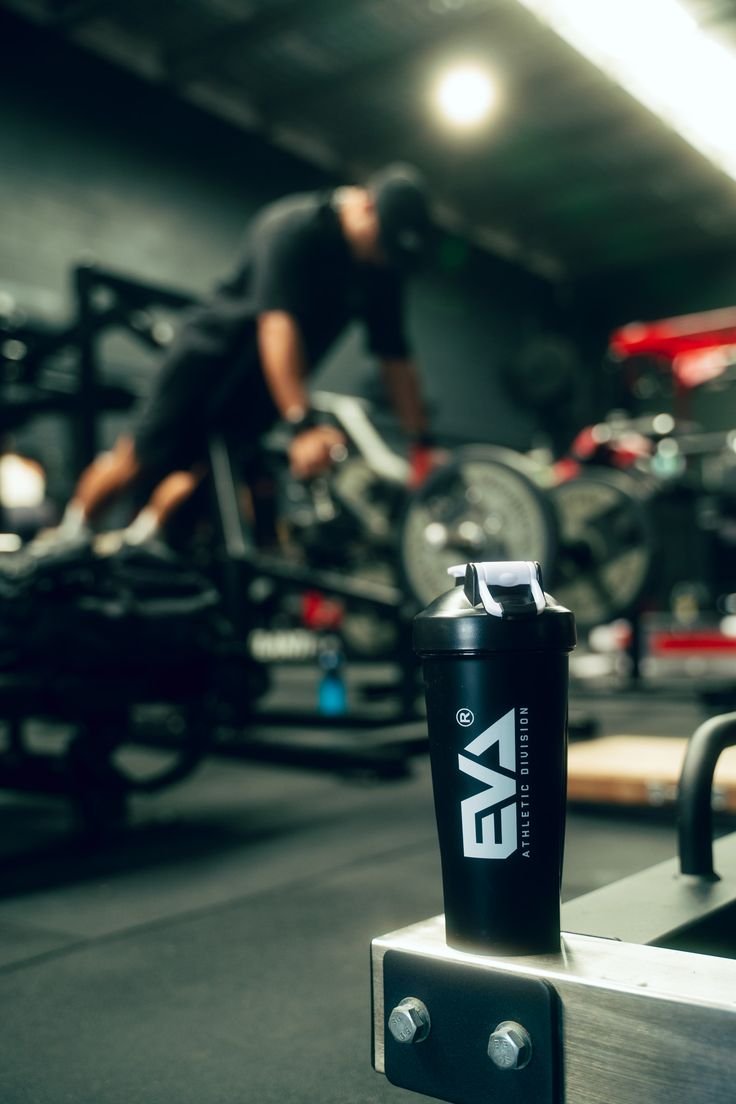 Shaker bottle on a gym bench with an athlete training in the background