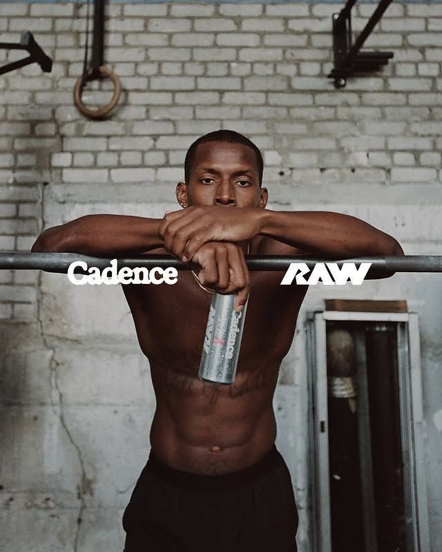 Athlete leaning on a pull-up bar in a brick gym, holding a drink can